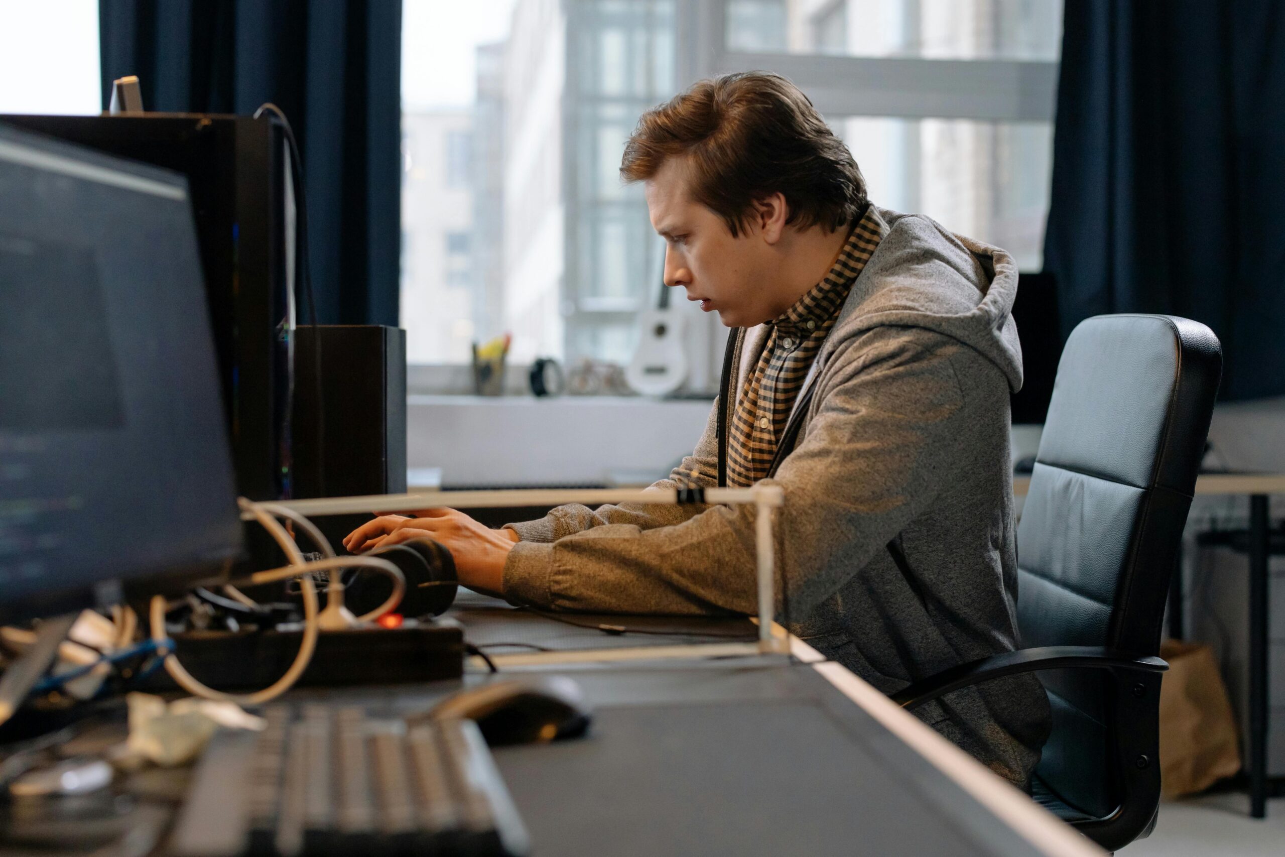 Free A concentrated professional working at a computer in a modern office setting. Stock Photo